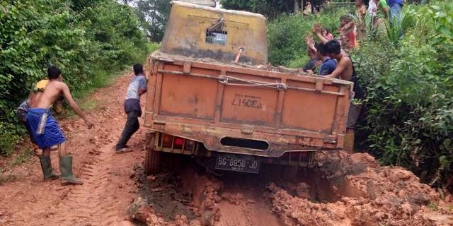 Mobil truk yang terlumpur didorong warga.